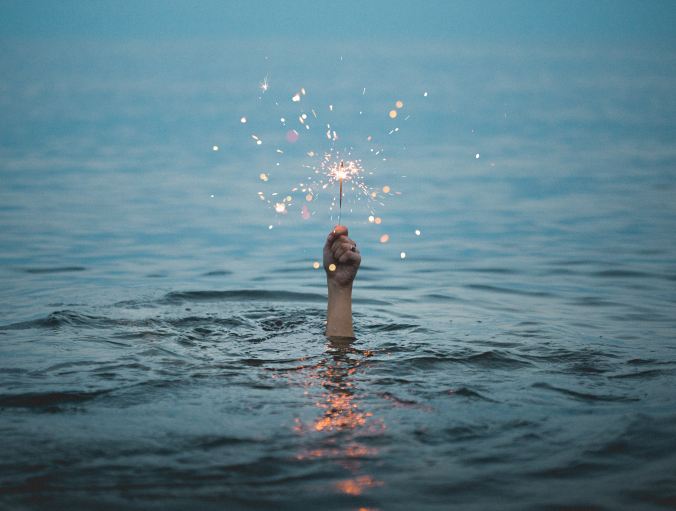 Hand holding fireworks with body submerged in water