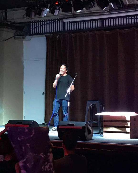 Stuart in black tee doing stand-up comedy